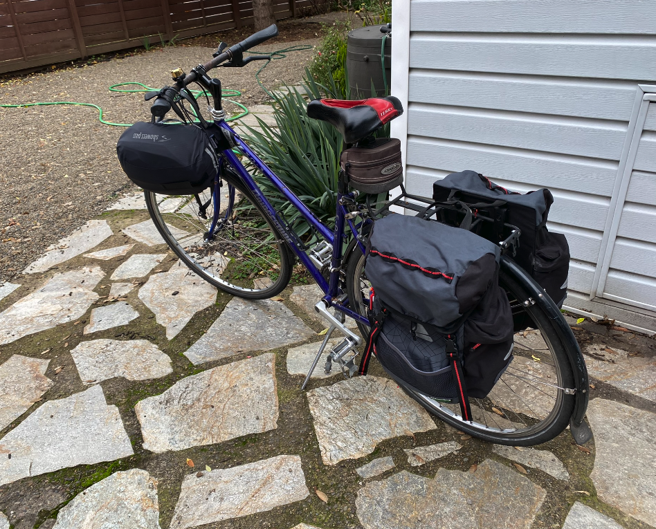 A bycicle loaded up with traveling gear